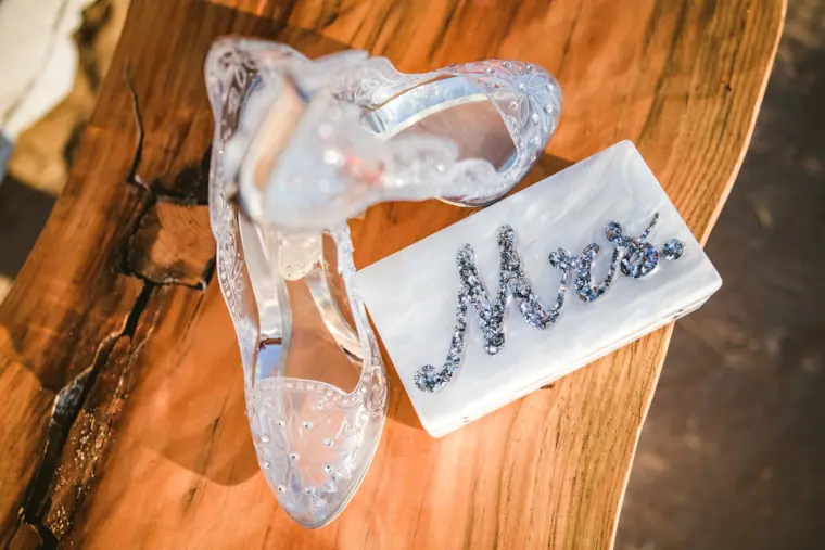 Clear glass bridal shoe beside a sparkly Mrs sign on wood at Sunset Ashram, Cala Conta