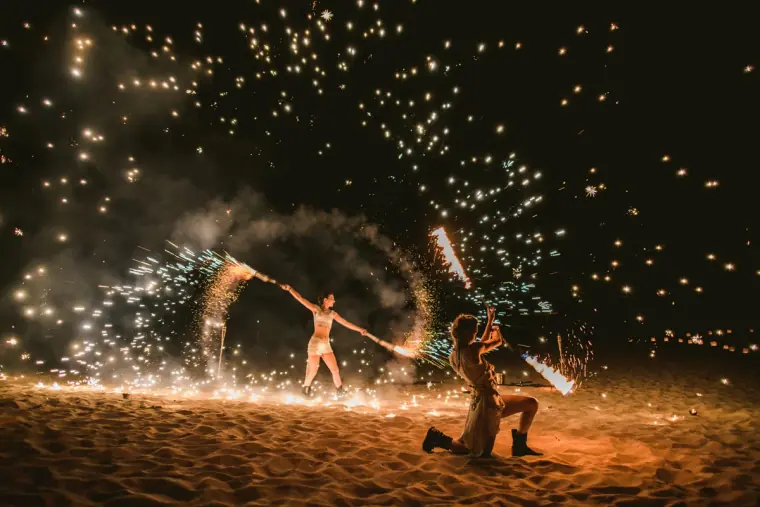 Fire performers spinning showers of sparks on the sand at night, Sunset Ashram, Cala Conta