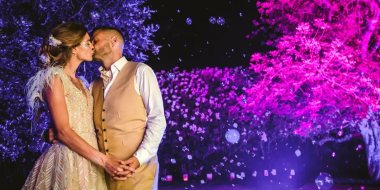 Kenton and Hassiba embracing before trees lit purple and pink at Kentiba Fest, Ibiza