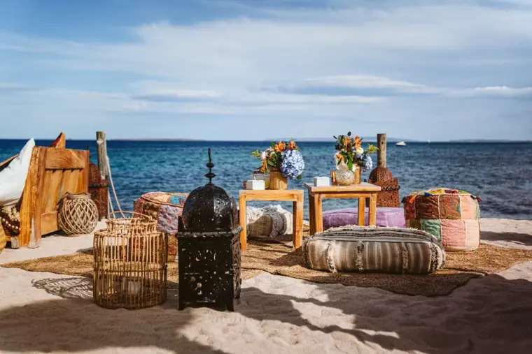 Boho beach lounge with lanterns, poufs and low tables by the sea at Restaurante La Escollera, Ibiza