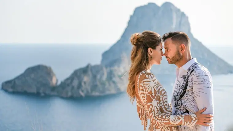 Kenton and Hassiba forehead to forehead with Es Vedrà rising behind, Ibiza