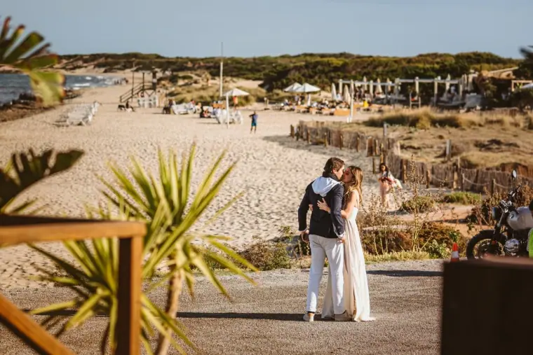 Antonia and Birger standing on a sandy beach path among palms near La Escollera, Ibiza