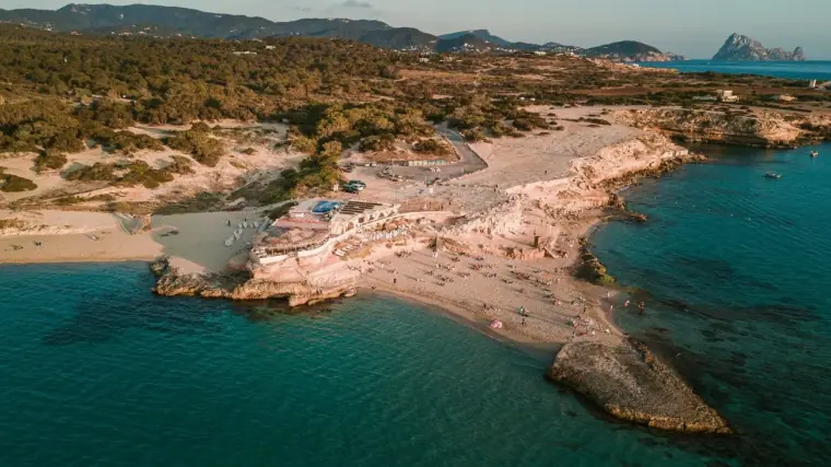 Aerial view of Cala Conta's rocky headland, white sand and turquoise sea, Ibiza