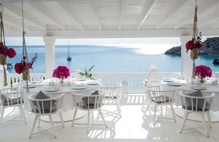 White terrace tables with pink flower centrepieces overlooking the sea at Cotton Beach Club, Ibiza