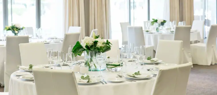 White-linen tables with floral centrepieces in a bright reception room at Ibiza Gran Hotel