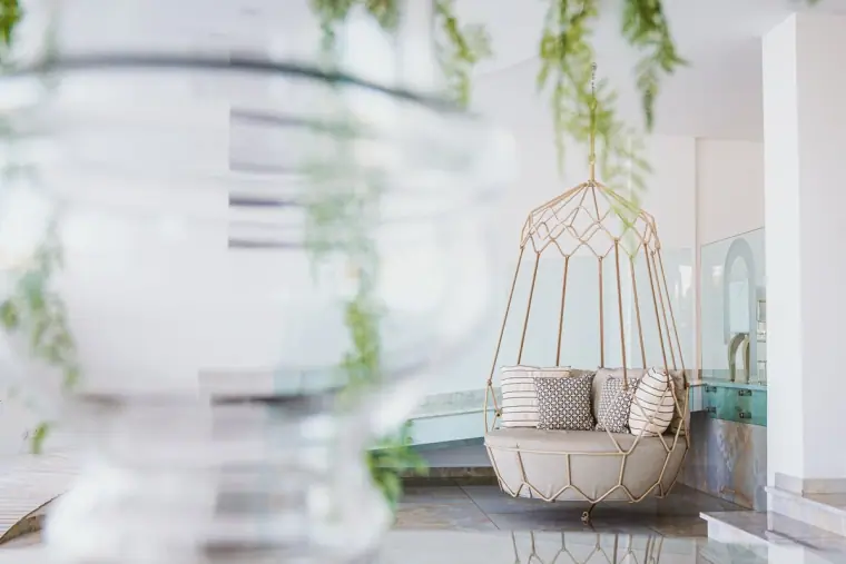 Hanging rattan egg chair beside the pool at Napa Suites, styled with cushions