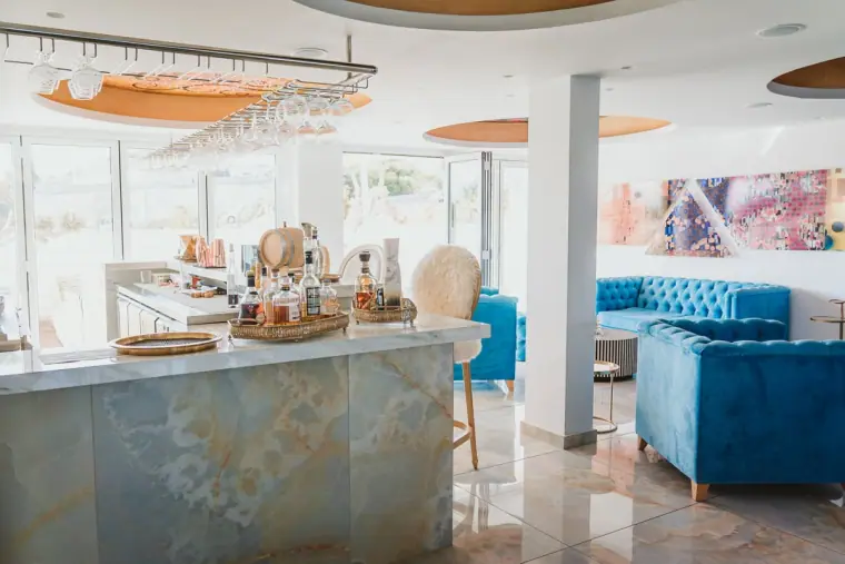 Marble-topped bar with spirits and blue velvet lounge seating at Napa Suites