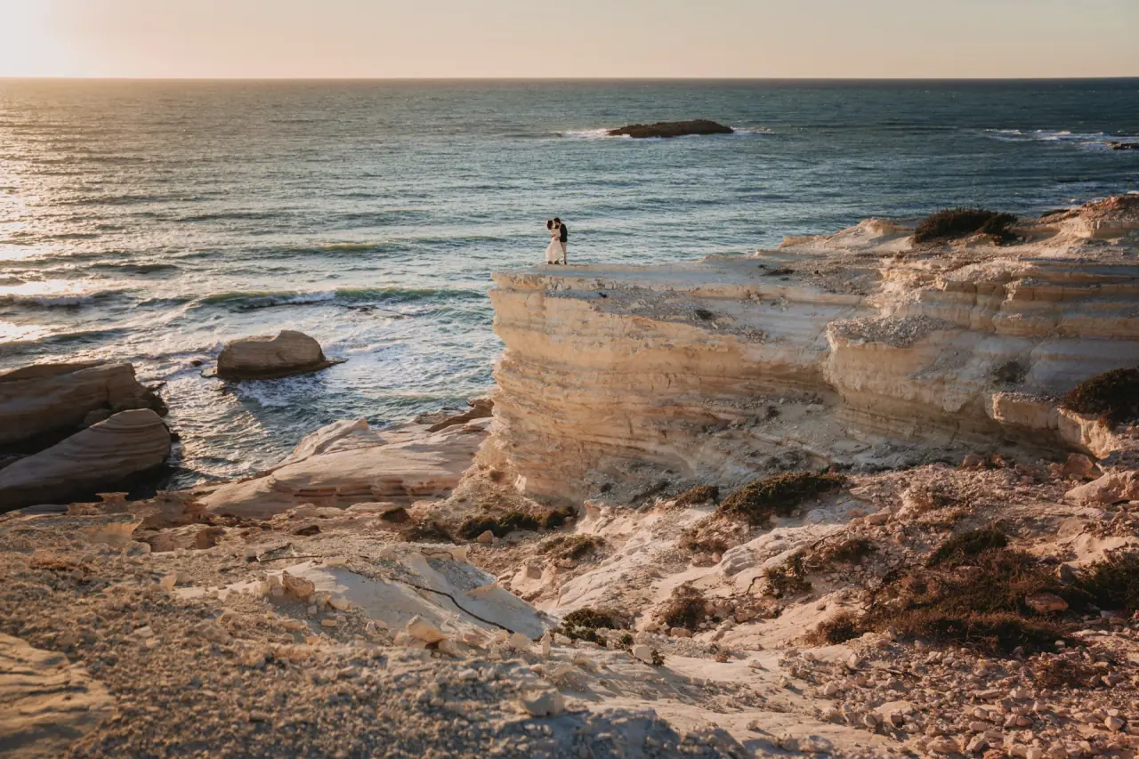 Aiko and Erez standing alone on a white clifftop above the sea, Sea Caves, Paphos