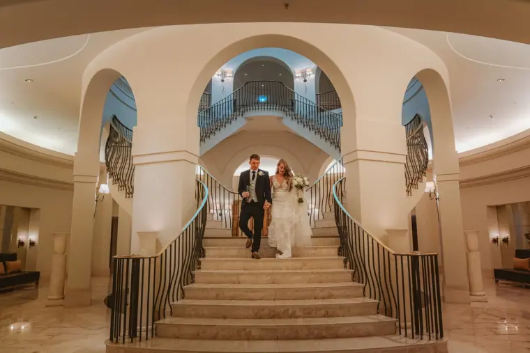 Carly and Jack descending a grand curved staircase at Anassa, Latchi