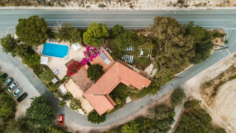 Drone view looking down on Vasilias Nikoklis Inn's pool, terracotta roofs and gardens
