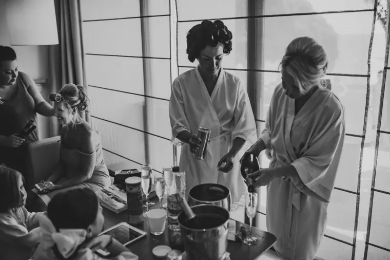 Black-and-white photo of bridesmaids in robes getting ready in a suite at Almyra