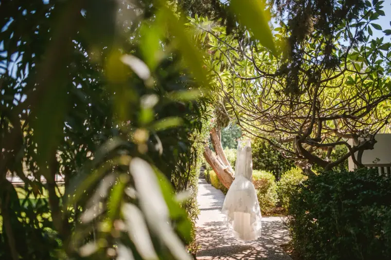 Wedding dress hanging from a tree in the leafy Almyra gardens