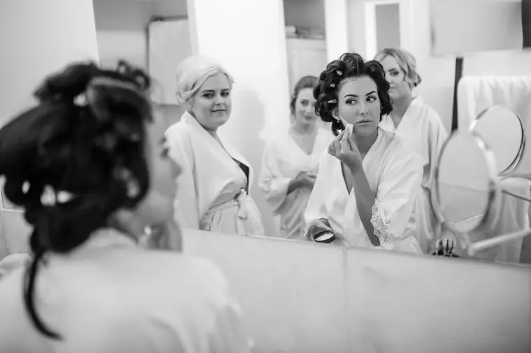 Black-and-white mirror reflection of Jaclyn and her bridesmaids in robes getting ready