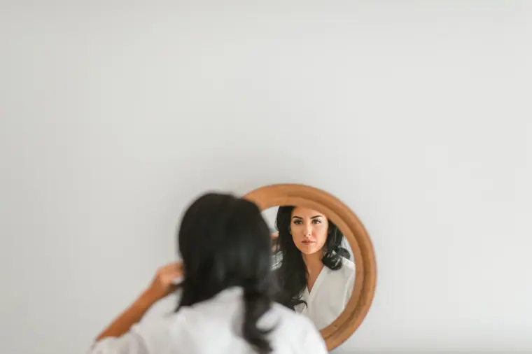 Jaclyn reflected in a round mirror as she finishes getting ready
