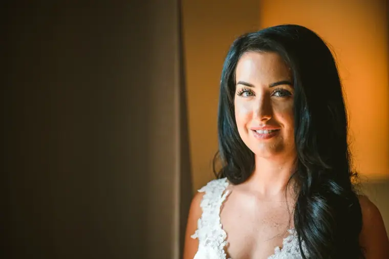 Smiling portrait of Jaclyn in warm light, dark hair falling past her shoulders