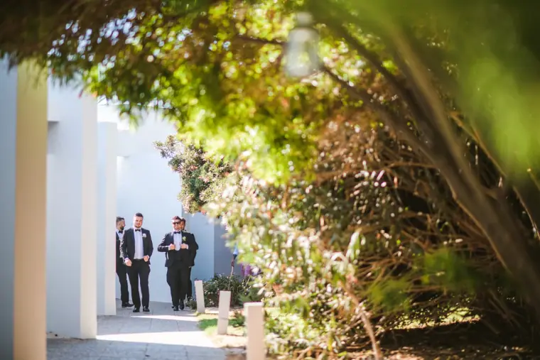 Groomsmen walking out through the Almyra gardens towards the ceremony