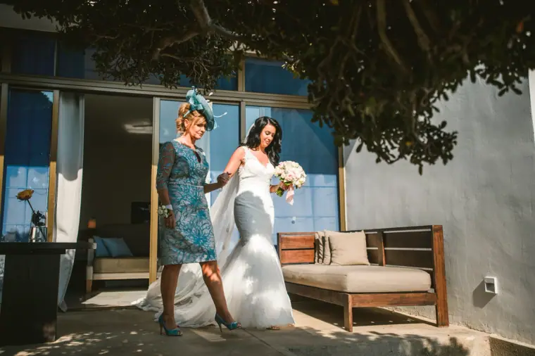 Jaclyn walking out with a woman in a blue dress and fascinator towards the ceremony