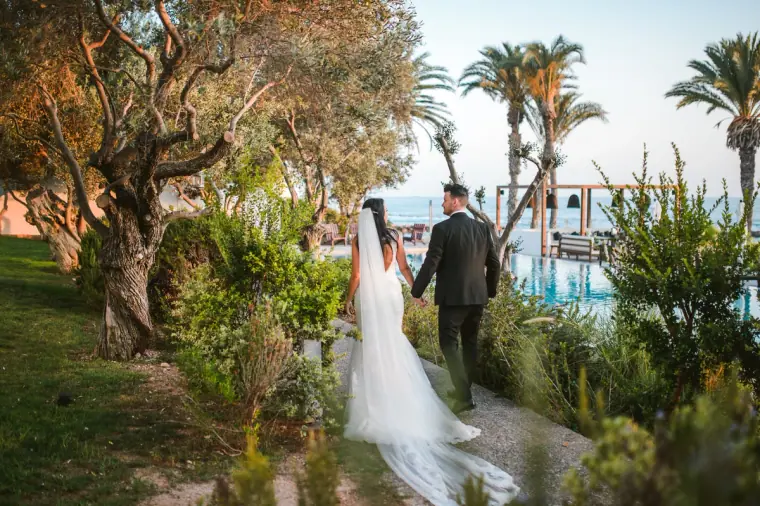 Jaclyn and Steven walking hand in hand through the gardens towards the sea at Almyra