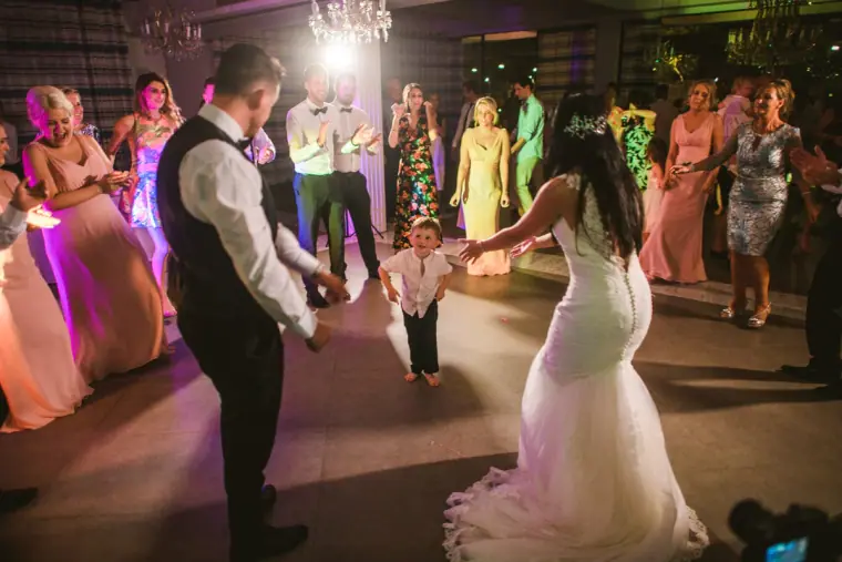Bridesmaids in pink and guests circling Jaclyn and Steven on a lively dancefloor
