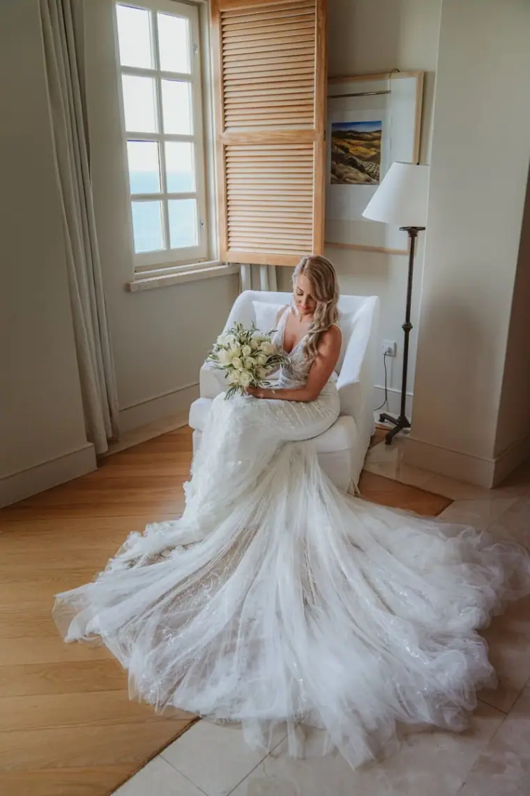 Carly sitting by a window in her voluminous tulle wedding dress at Anassa Hotel