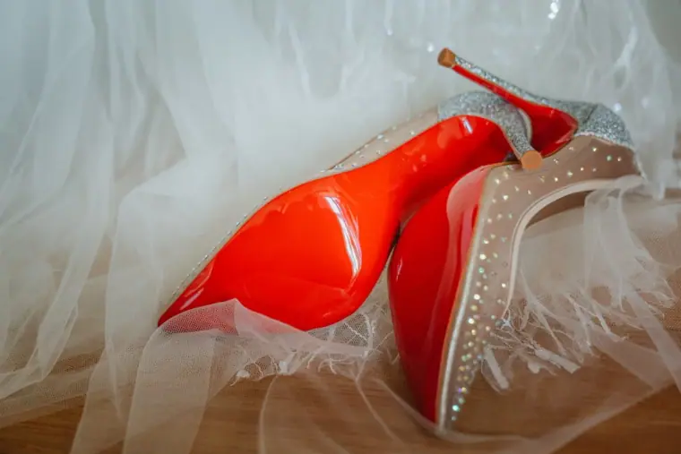 Bride's red-soled studded heels resting on white tulle