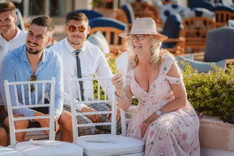 Smiling guests seated on white chairs waiting for the ceremony to begin