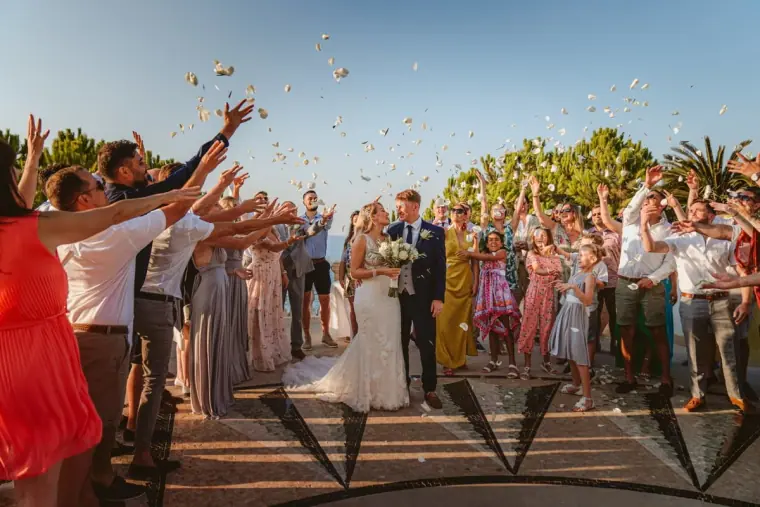 Guests throwing petal confetti as Carly and Jack walk back up the aisle
