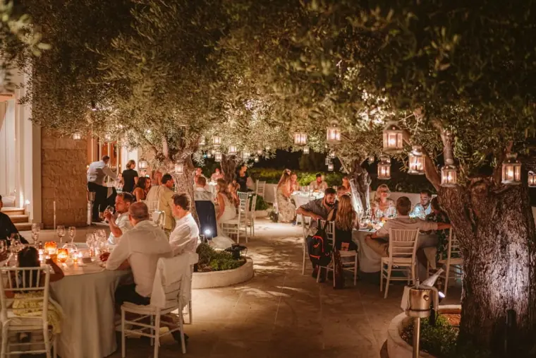 Guests dining beneath lantern-lit olive trees at the reception at Anassa Hotel