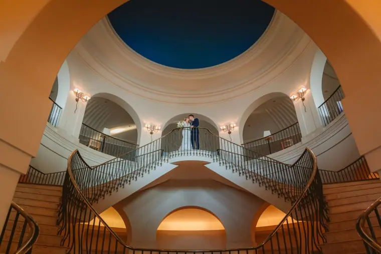 Couple on the curved double staircase beneath the domed ceiling at Anassa Hotel