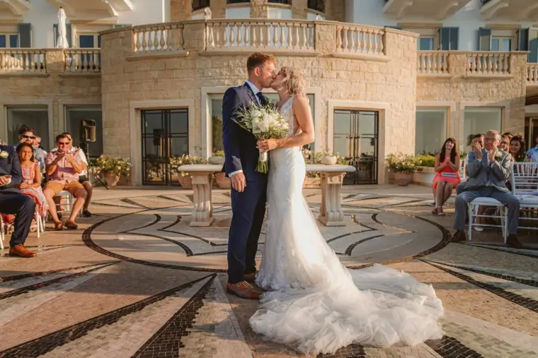 Carly and Jack embracing on the mosaic terrace as guests watch at Anassa Hotel
