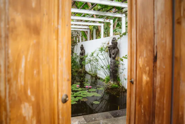 Wooden doors opening onto a whitewashed courtyard with stone statues at Atzaro, Ibiza
