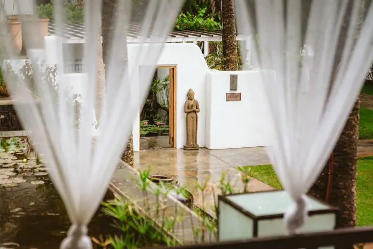 Sheer white curtains framing a garden courtyard and statue at Atzaro, Ibiza
