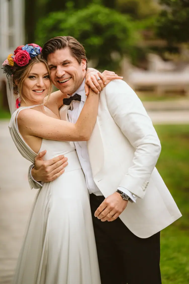 Antonia in a flower crown hugging Birger in his white tuxedo jacket at Atzaro