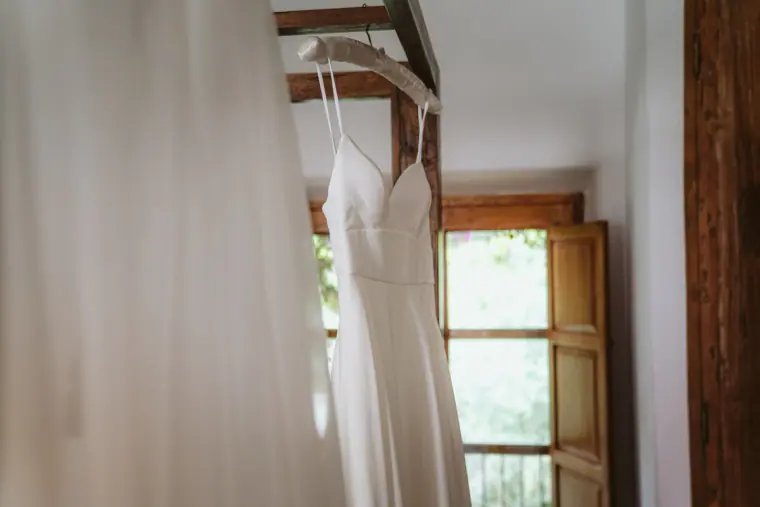 White wedding dress hanging in a doorway of a rustic room at Atzaro, Ibiza