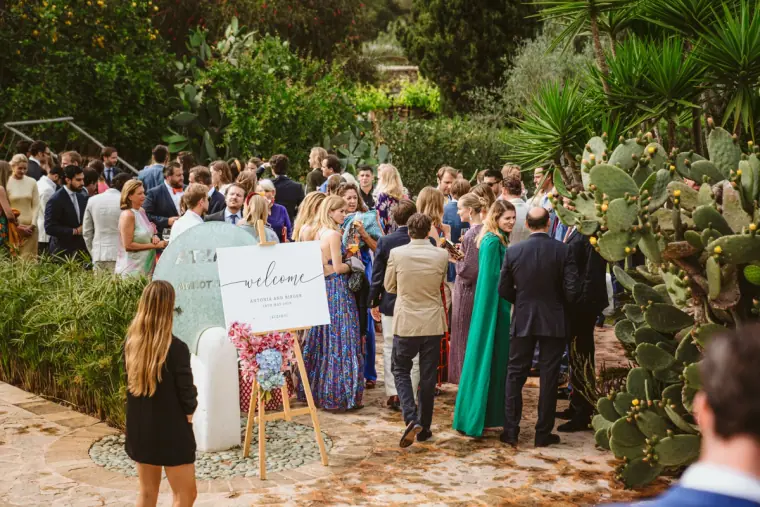 Guests gathering in the garden by a welcome sign before the ceremony at Atzaro