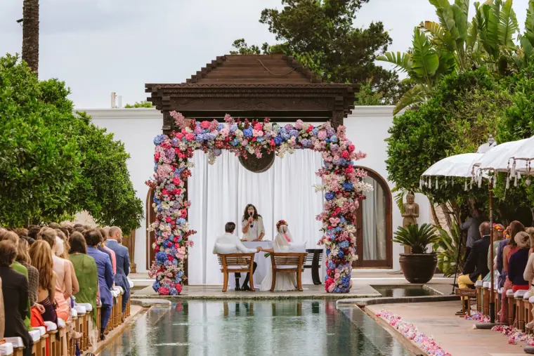 Celebrant addressing the couple as guests sit either side of a reflecting pool at Atzaro, Ibiza