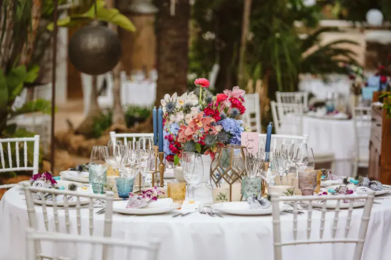 Reception table with colourful flowers and blue glassware in the garden at Atzaro
