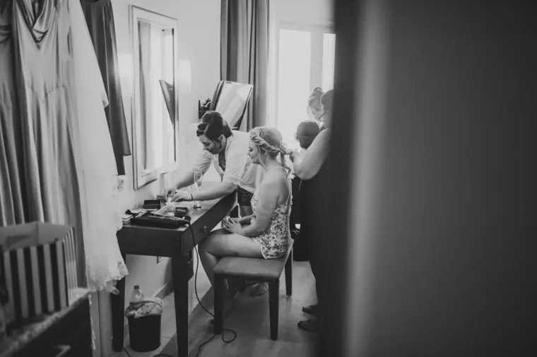 Black-and-white photo of bridesmaids doing hair and make-up in a hotel room