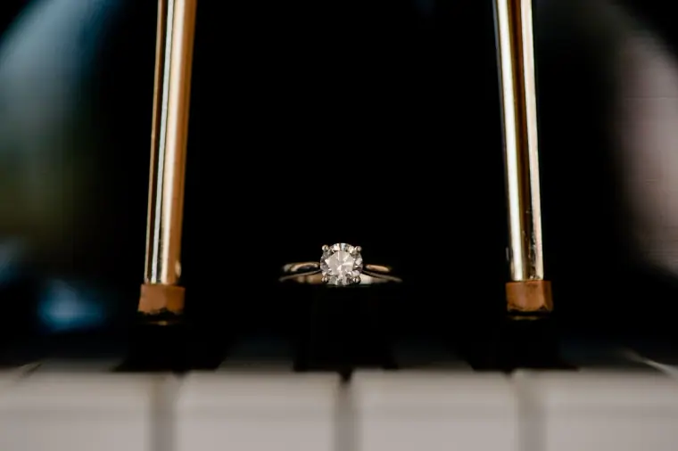 Diamond engagement ring resting on the keys of a black piano