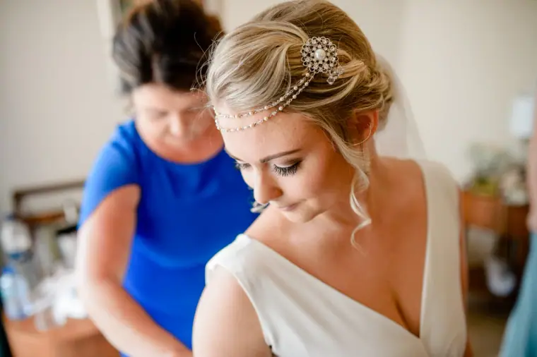 Woman in blue fastening the back of Francesca's wedding dress