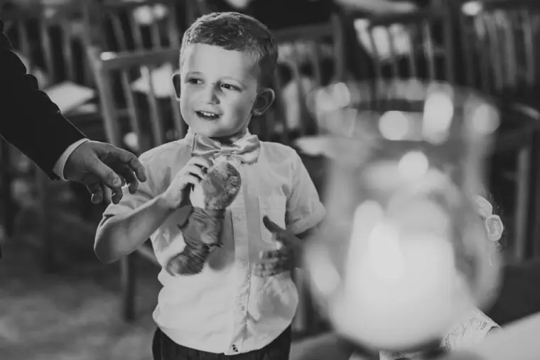 Black-and-white photo of a young page boy holding a soft toy in the church