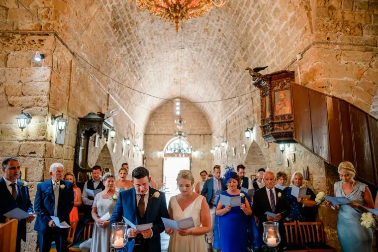 Couple and guests during the ceremony beneath the stone vaults of Ayia Kyriaki