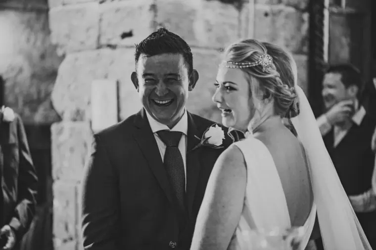 Black-and-white photo of Francesca and Stephen laughing together at the altar
