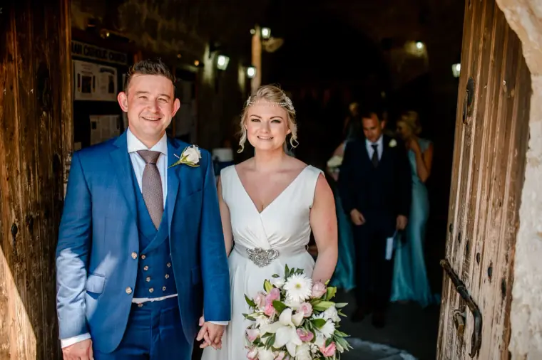 Newlyweds stepping out through the wooden church door at Ayia Kyriaki, Paphos