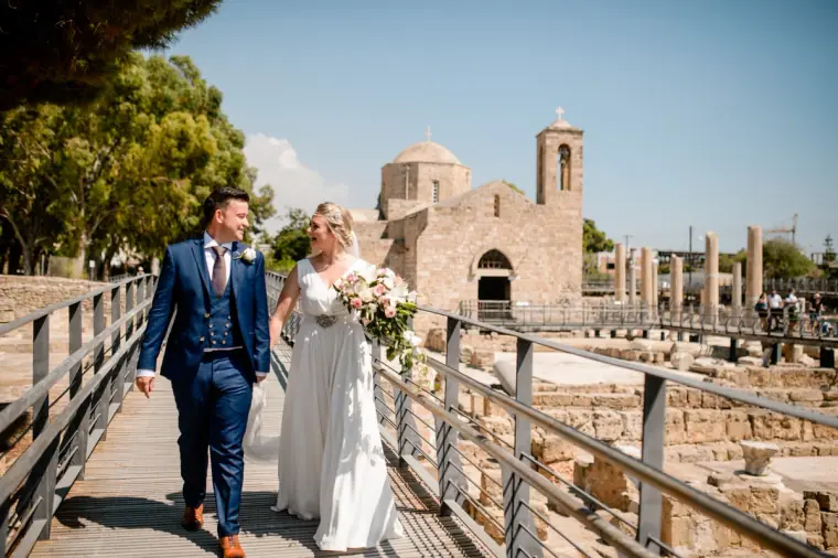 Bride and groom walking along the boardwalk past the ancient ruins at Ayia Kyriaki
