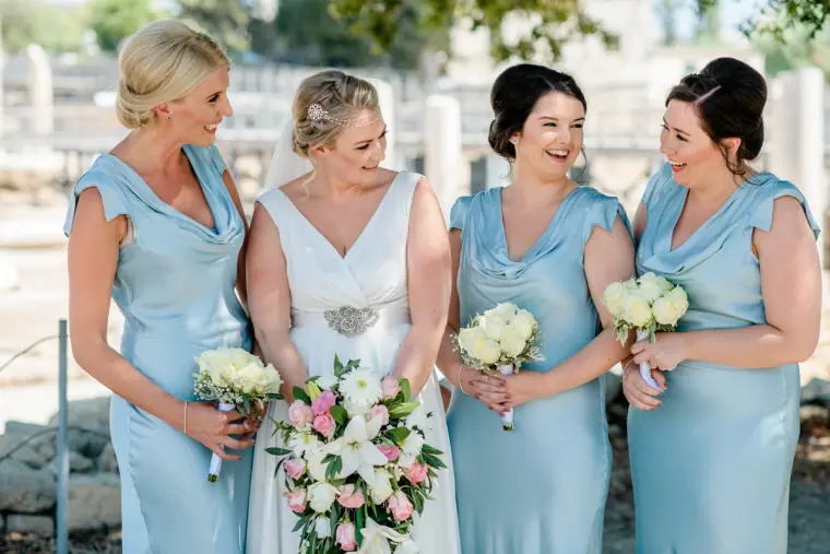 Francesca laughing with her bridesmaids in pale blue satin dresses