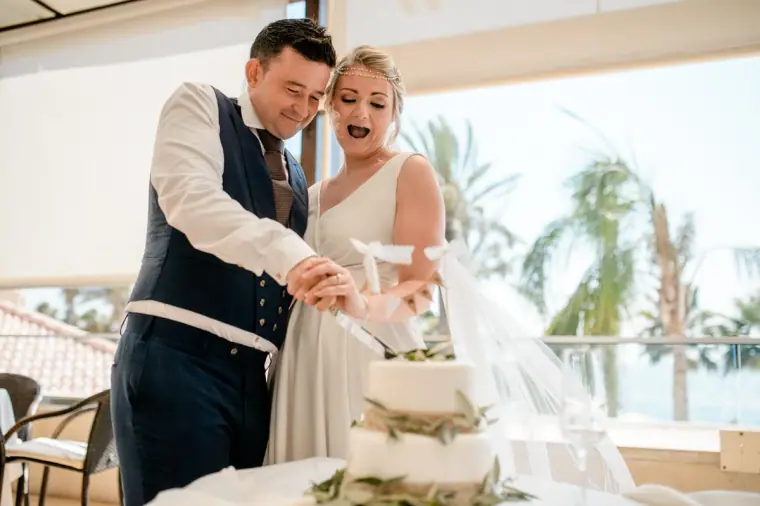 Francesca and Stephen laughing as they cut their wedding cake