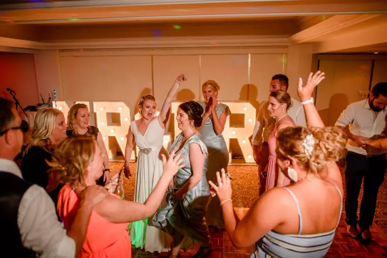 Bride dancing with guests in front of the MR & MRS light-up letters
