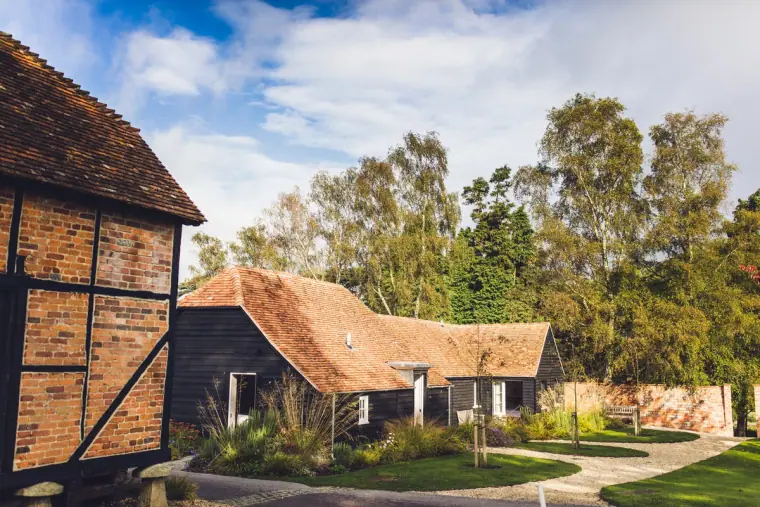 Timber-framed barns and gardens under a blue sky at Wasing Park, Berkshire