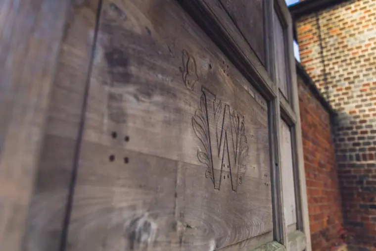 Close-up of a monogram carved into a weathered wooden door